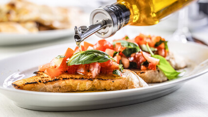 Detail of olive oil poured over bruschetta with basil and tomatoes
