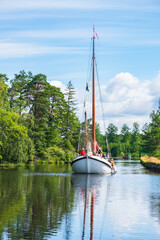 Canal with an old sailboat in a summer landscape