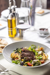 Set table with steak and salad with condiments next to it in a restaurant