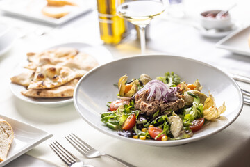Salad with tuna, greens, onion, avocado and cherry tomatoes served on a table