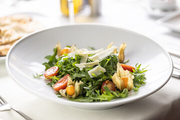 Ruccola salad with cherry tomatoes, physalis and parmesan cheese shavings