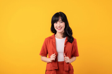 Portrait young beautiful asian woman happy smile dressed in orange clothes isolated on yellow studio background. Asian girl human face.