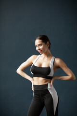 Fototapeta na wymiar Young fitness woman wearing sportswear standing over dark wall background.