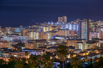 Fototapeta premium City, buildings and urban landscape at night, skyline and location with architecture, landmark and travel. Cityscape, skyscraper and Cape Town view for tourism, traveling and background destination