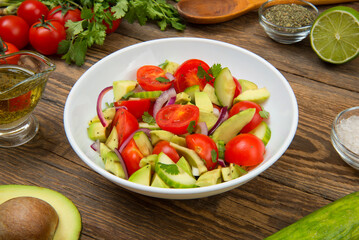 Avocado, tomato, cucumber and onion salad. with ingredients on an old rural table. - 611240052
