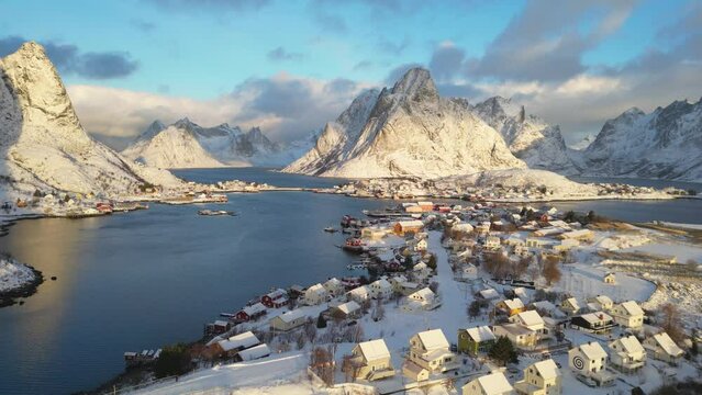 Top aerial view Beautiful landscape of snowy mountain and fishing village on the coastline in winter at Lofoten Islands. Norway with red rorbu houses in winte