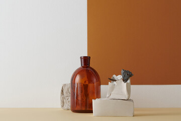 Horizontal shot of contemporary color-blocking still life composition with brown glass vessel, dried lotus and gypsum bricks against white and terracotta wall background, copy space