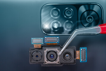Fototapeta na wymiar Close-up of a smartphone's triple camera module held with tweezers