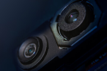 Close-up of a smartphone's triple camera held with tweezers