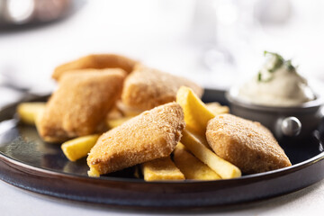 Fried breaded cheese with french fries and mayonnaise served on a restaurant plate