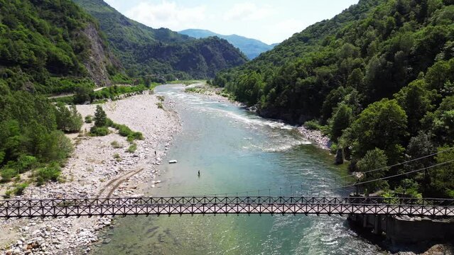 Drone flight over a wooden Tibetan suspended bridge that joins the river banks - view from the drone in Alagna Val Sesia Piedmont Alps mountains - travel concept journey in adventure natural trip 