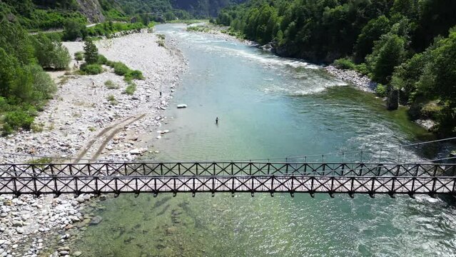 Drone flight over a wooden Tibetan suspended bridge that joins the river banks - view from the drone in Alagna Val Sesia Piedmont Alps mountains - travel concept journey in adventure natural trip 