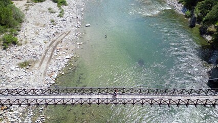 Drone flight over a wooden Tibetan suspended bridge that joins the river banks - view from the...