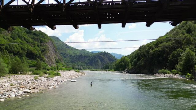 Drone flight over a wooden Tibetan suspended bridge that joins the river banks - view from the drone in Alagna Val Sesia Piedmont Alps mountains - travel concept journey in adventure natural trip 