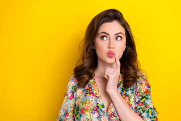 Fototapeta na wymiar Photo of doubtful unsure lady wear retro flower print blouse finger lips looking empty space isolated yellow color background
