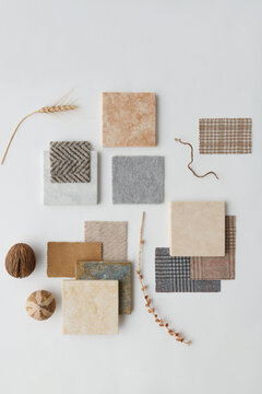 Vertical top-down flat lay shot of stone and ceramic piles, pieces of fabrics, seeds and dried plants on white surface