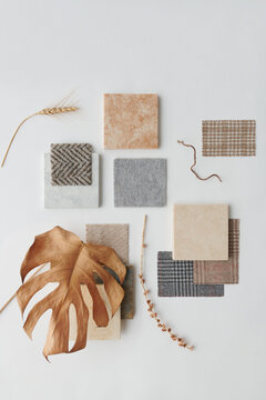 Vertical from above view flat lay shot of stone and ceramic piles, pieces of fabrics and dried plants on white surface