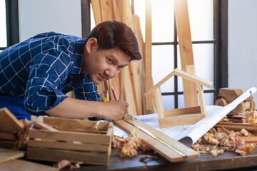 Asian young carpenter working with equipment on wooden table in carpentry shop, concept of  works in a carpentry shop