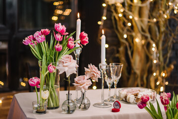 Location for surprise marriage proposal. Engagement, ring in red box. Decoration flowers, decor candles. Luxury romantic date. Candlelight dinner setup table for couple on Valentines day in restaurant