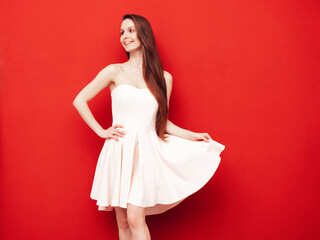 Portrait of young winsome woman in romantic attire pretty smiling on red background. Slim female in pure pink dress posing in studio. Cheerful model. Isolated. Long hair
