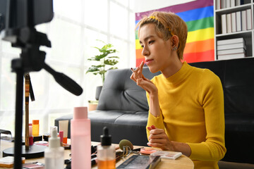 Smiling Asian gay man blogger filming daily makeup routine tutorial on smartphone. LGBTQ, domestic life and beauty concept