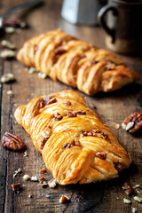 Freshly baked pecan nut pastry braid on dark rustic wooden background