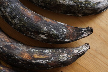 Mouldy plantains or bananas on wooden background