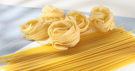 Raw Italian pasta fettuccine, spaghetti, fusilli, penne. traditional italian food close up. types of uncooked pasta on a white background. egg noodles. mediterranean cuisine.