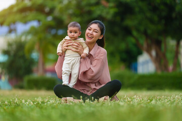 mother holding with infant baby while sitting in grass field