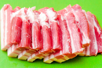 A few pieces of raw meat pork.A cut piece of pork close-up, fresh pork meat before baking,cooking.Green background.Closeup.