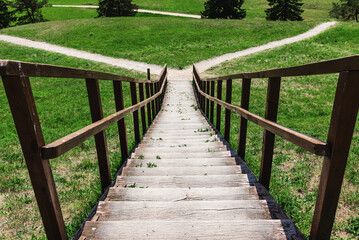 Wooden stairs gangway with a field and trees.path selection,which way to turn.Summer day. Nature landscape background.