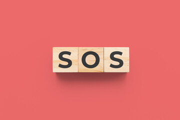 SOS (Save Our Souls) wooden cubes on red background