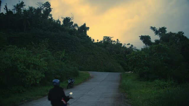 A scooter drives down the road into the jungle on a tropical island in the Philippines
