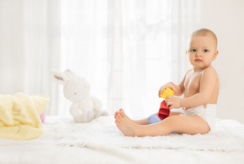 Little baby in nappy playing with toys