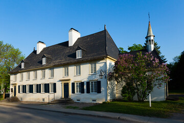 Fototapeta na wymiar The 18th Century Mauvide-Genest manor with small chapel seen from the street in spring, Saint-Jean, Island of Orleans, Quebec