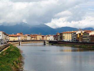 Fototapeta na wymiar The bridge over the river in the ancient city on the background of the mountains in the clouds