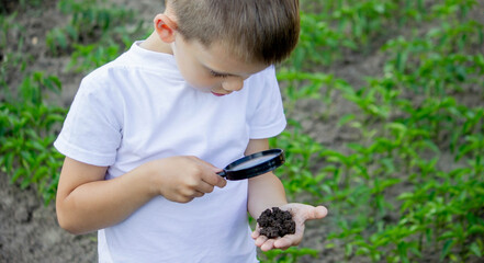 the child holds the earth in his hand and looks through a magnifying glass.