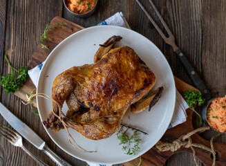 Roast whole chicken with carrot salad on wooden table