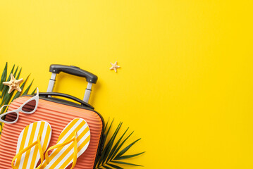 Dream trip concept. Top view photo of orange suitcase with slippers and sunglasses on it with palm leaves and starfish on isolated bright yellow background with copyspace