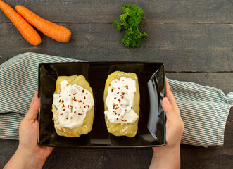 Cabbage rolls with sour cream on a black plate in women's hands.Top view