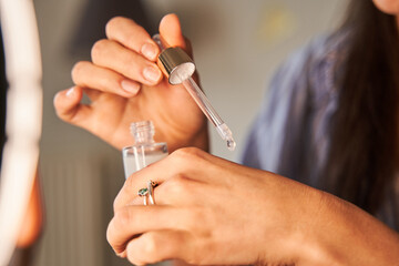 Cropped view of the caucasian woman hand applying face serum on her hand