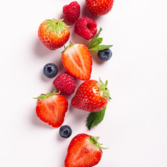 Fototapeta na wymiar Summer berry fruits with strawberry, raspberry and blueberry on white background, top view, flat lay. Creative food concept with copy space