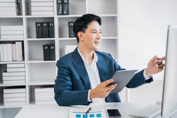 Naklejka premium Male businessman using a tablet and computer to analysis graph company financial in office.