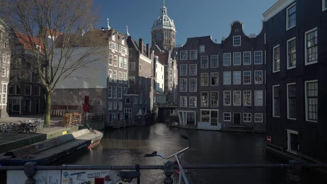 Empty street of De Wallen red light district in old Amsterdam, Canal Oudezijds Voorburgwal, Bridge and Basilica of Saint Nicholas church during Covid 19 pandemic
