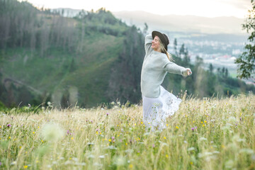 Fototapeta premium Happy woman enjoying outdoors, stay on the green grass on the forest peak of mountain.