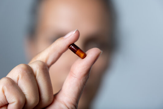 gros plan d'une main tenant une pilule qui pourrait &ecirc;tre une vitamine ou un m&eacute;dicament