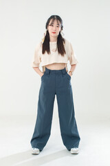 Portrait isolated cutout studio shot of Asian young cute female teenage fashion model with pigtails braids hairstyle in casual trendy wear standind posing look at camera on white background