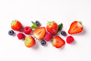 Summer composition with strawberry, raspberry and blueberry over white background, top view, flat lay. Creative food concept with copy space