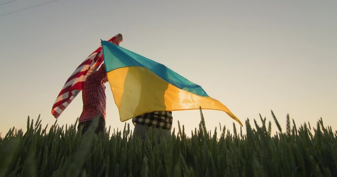 Young couple with usa and ukraine flags in wheat field. Low angle view