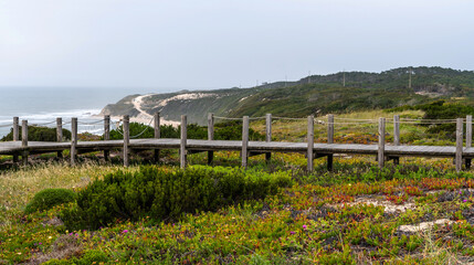 Fototapeta premium Majestic coastline looking the Atlantic Ocean. View of nature landscape shore. Wooden walkway to the beach, Portugal.